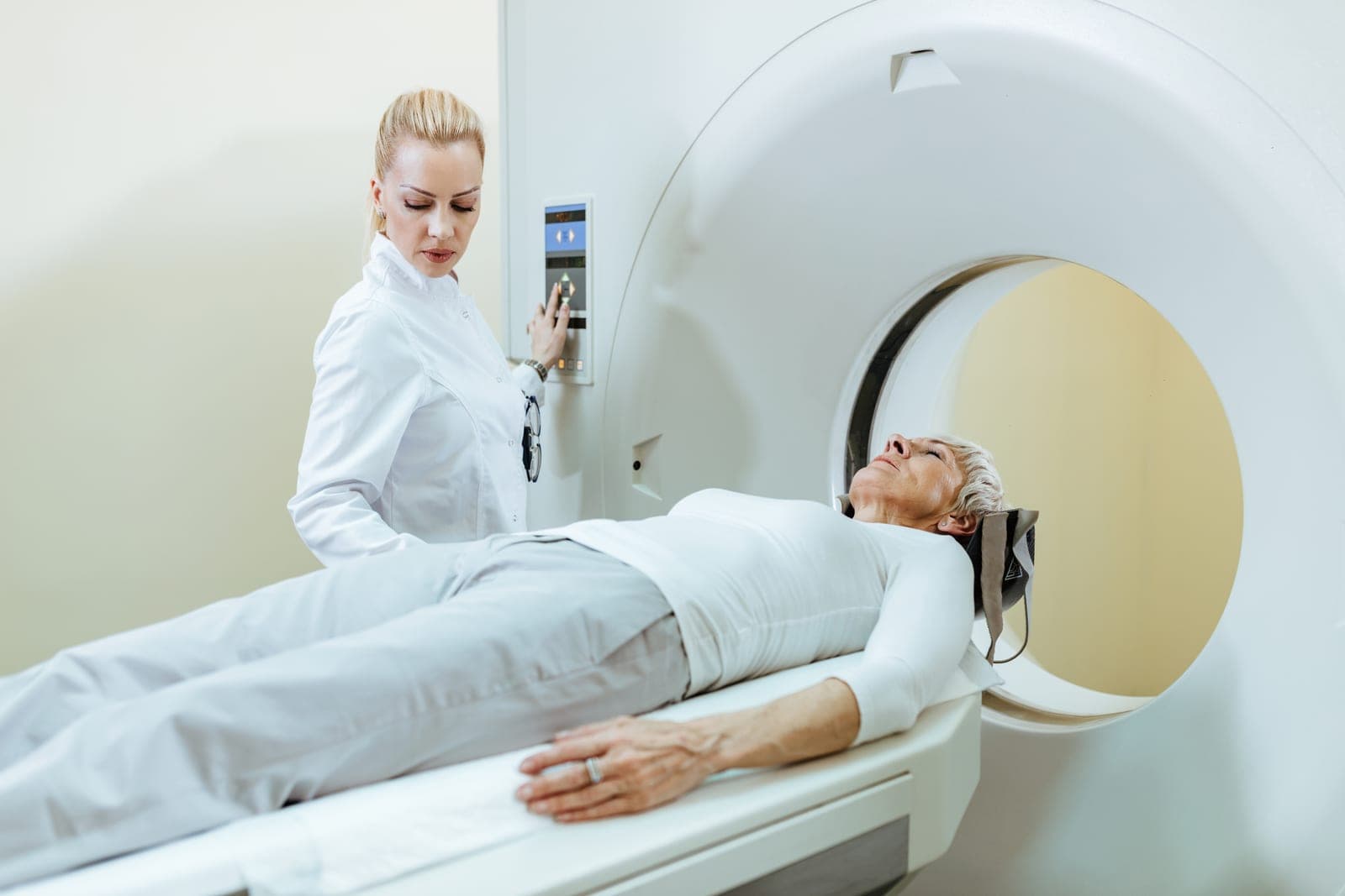 Paciente deitada na maca do tomógrafo sendo acompanhada pela equipe médica antes do exame de angiotomografia