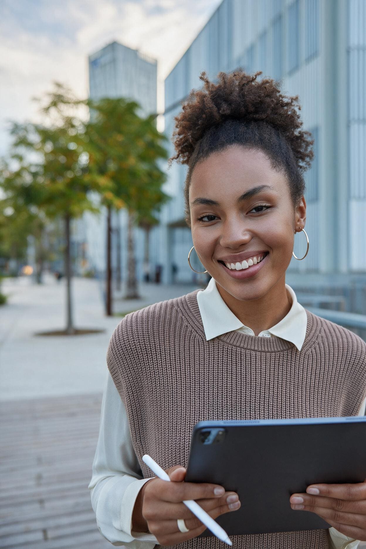 Profissional usando a plataforma Clini+ em um tablet, em frente a um prédio corporativo