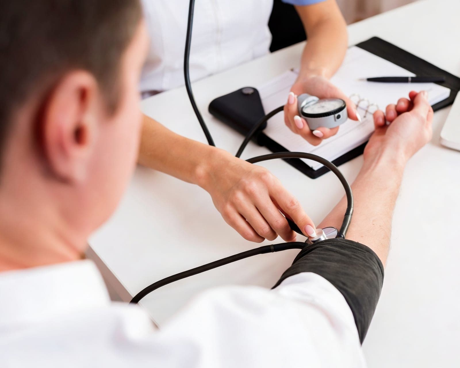 Médico medindo a pressão arterial de paciente em consulta