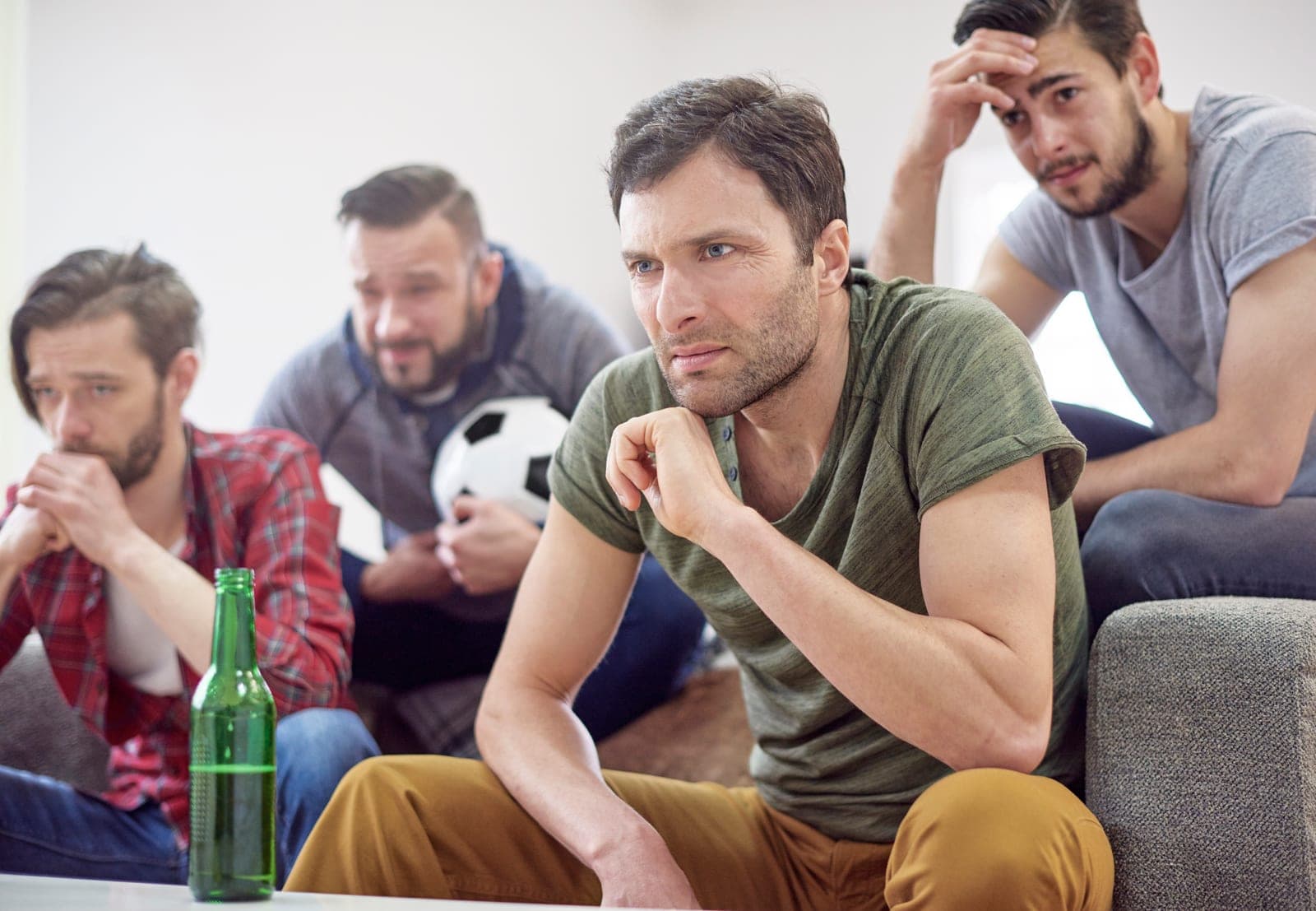 Grupo de amigos tenso assistindo a uma partida de futebol, refletindo a pressão emocional das apostas esportivas