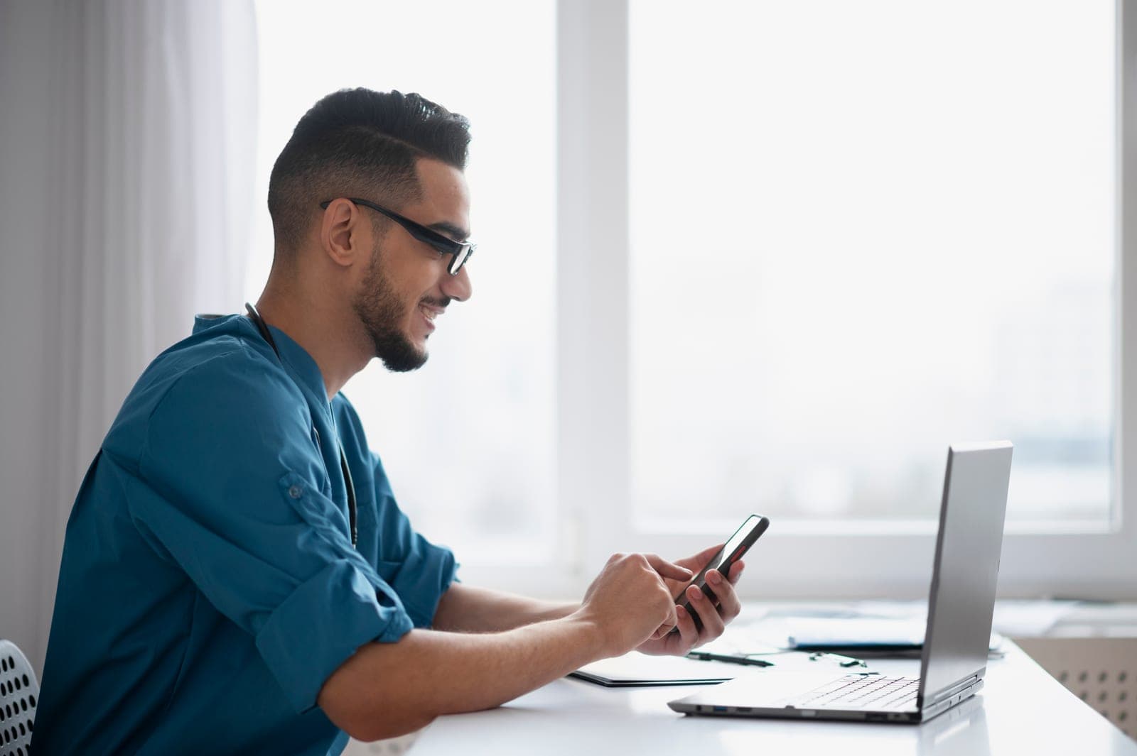 Médico de plantão atendendo pelo celular e pelo notebook