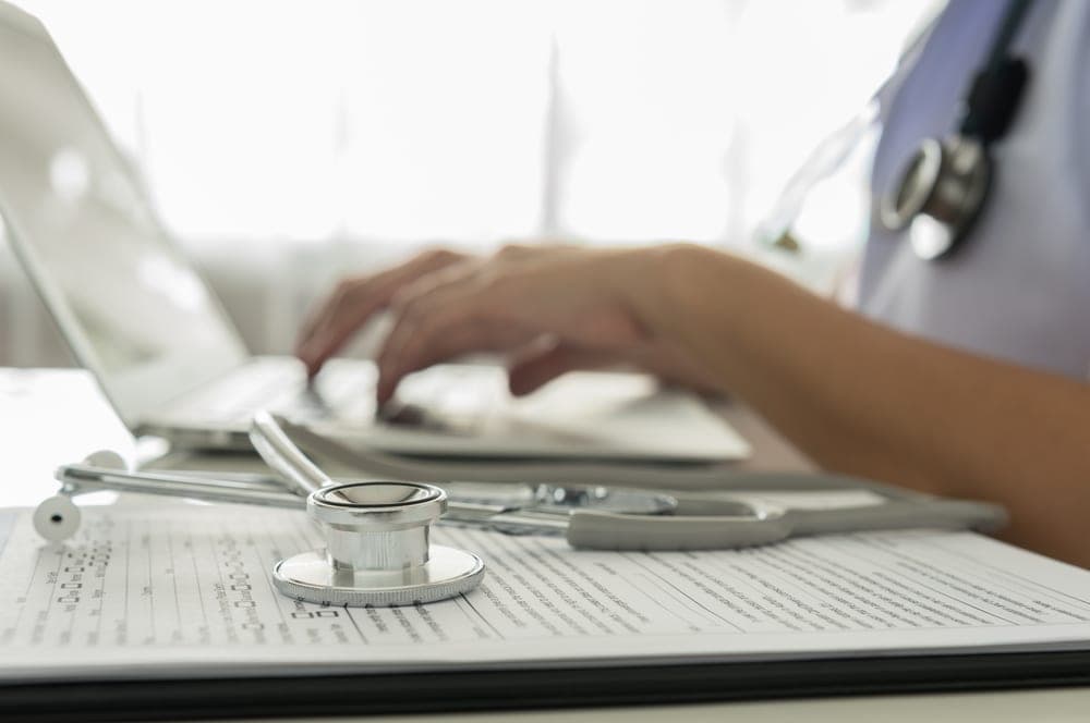 Médico analisando prontuário eletrônico em laptop