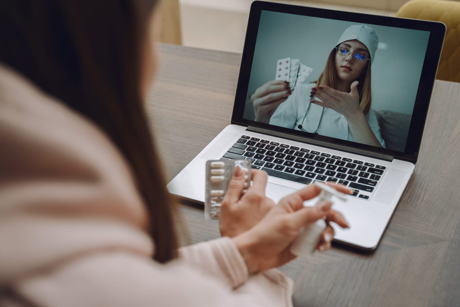 Paciente em teleconsulta por vídeo recebendo orientação da médica sobre a medicação