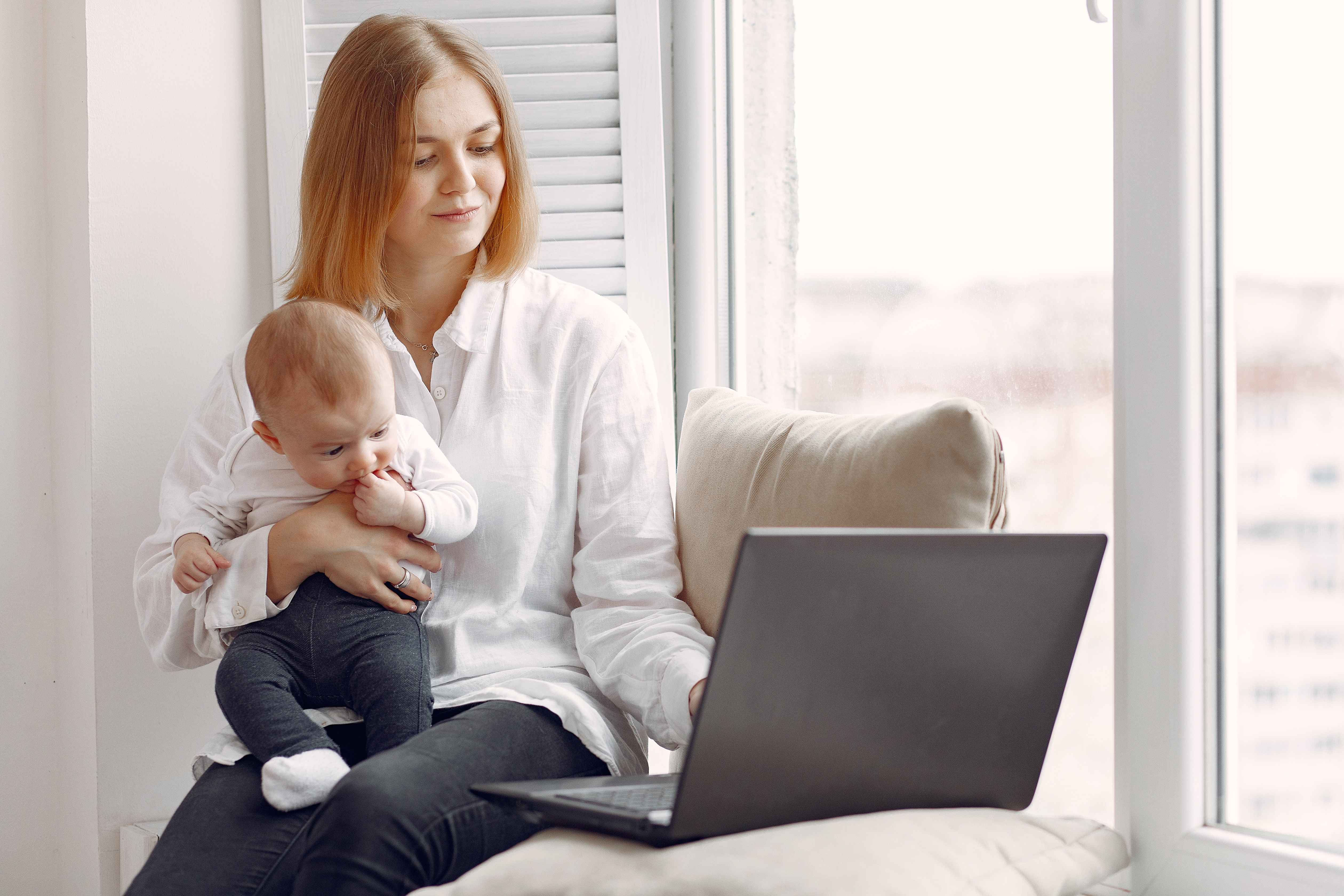 Mãe com o bebê no colo em casa, em um momento tranquilo do dia a dia pós-parto